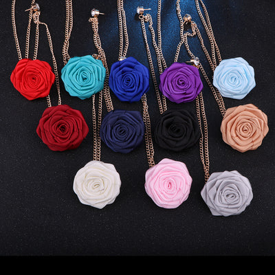 Colorful rose-shaped brooches on gold chains against a black background