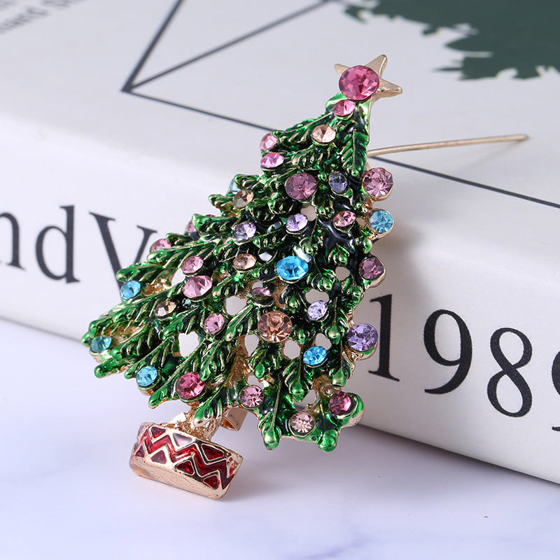 Decorative brooch shaped like a Christmas tree with colorful gemstones on a newspaper background.