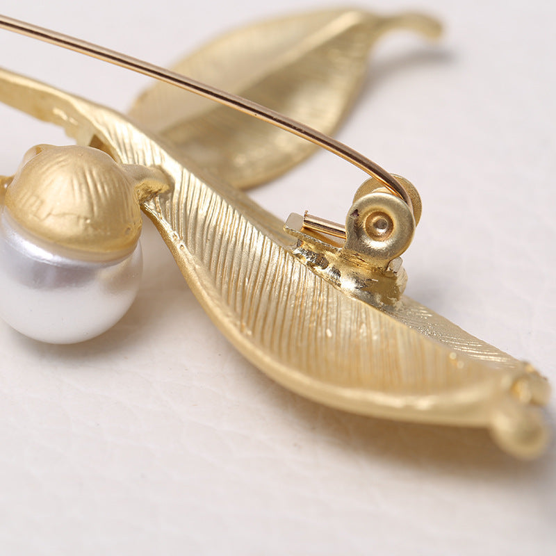 back side of a Gold brooch with pearl accent on a light background