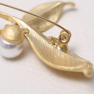 back side of a Gold brooch with pearl accent on a light background