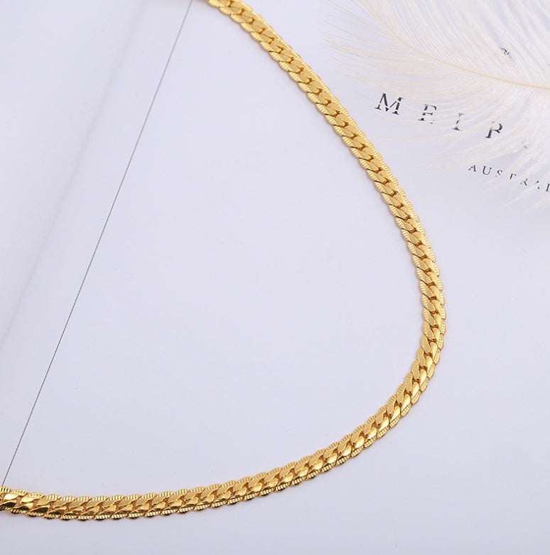 Gold chain necklace on a light gray background