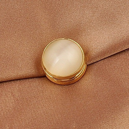 cat eye magnetic brooch with gold trim on a brown fabric background