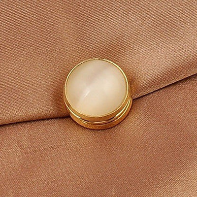 cat eye magnetic brooch with gold trim on a brown fabric background
