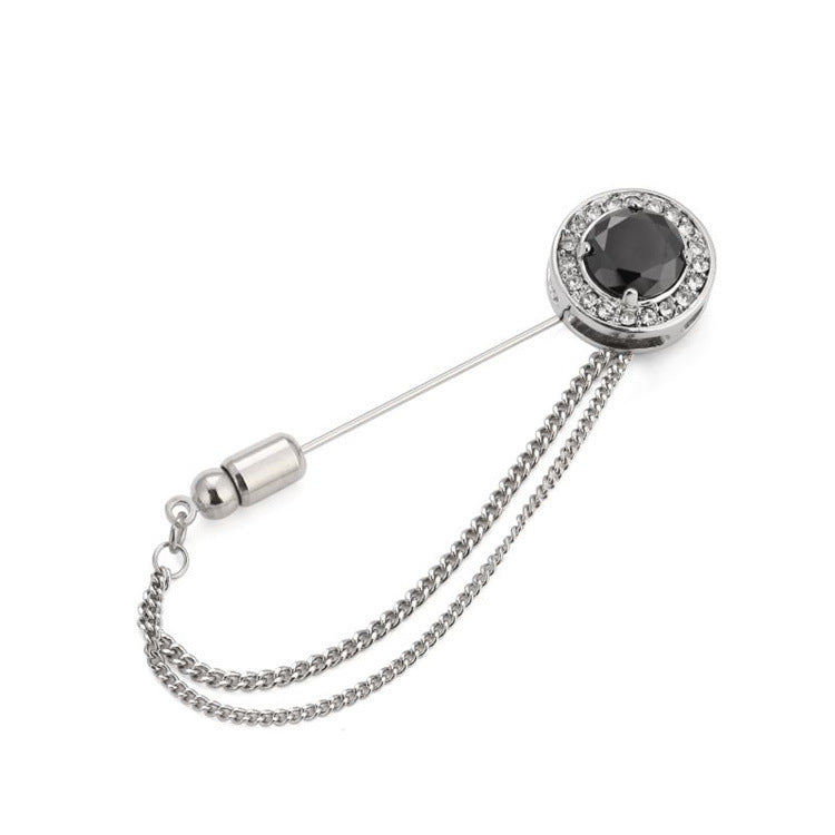Silver brooch with black gemstone and chain on a white background