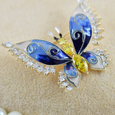 Butterfly-shaped jewelry with blue, yellow, and white colors on a beige background
