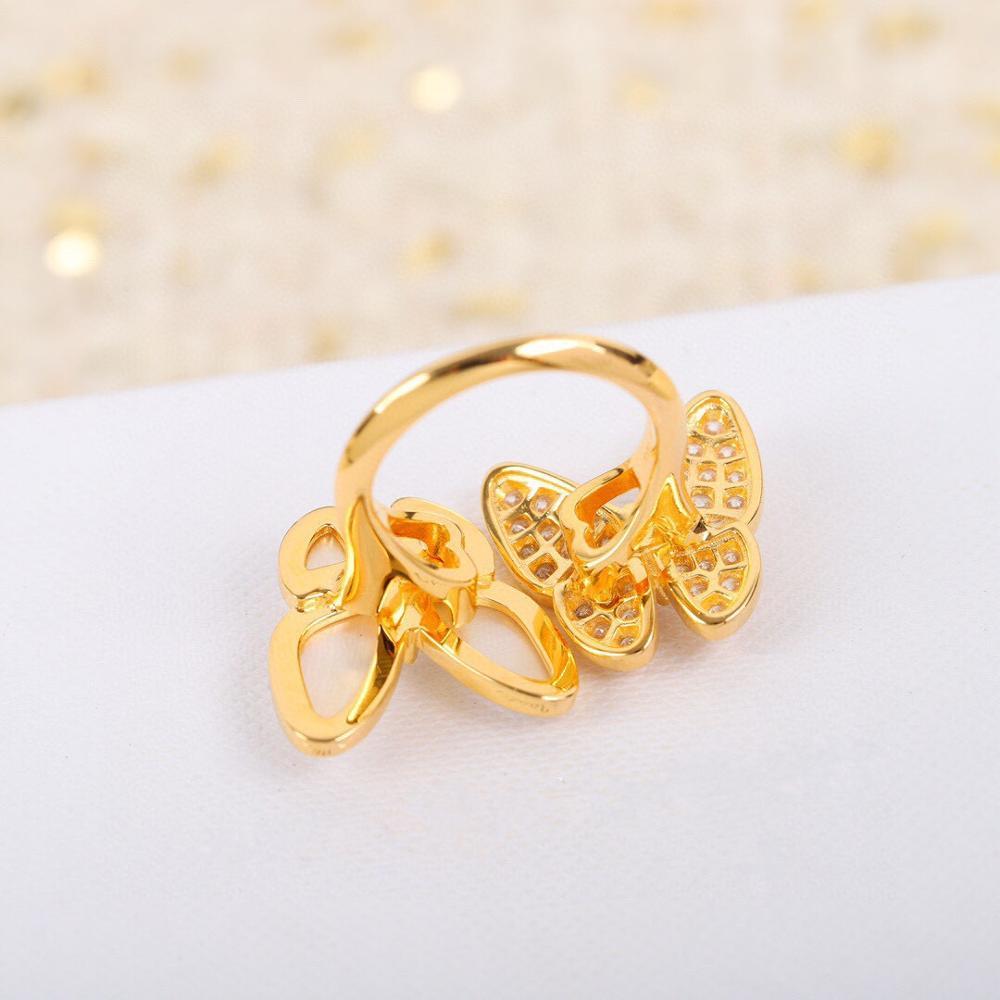 Back view of a Gold butterfly-shaped ring on a white surface with a soft, blurred background