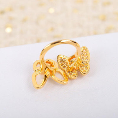 Back view of a Gold butterfly-shaped ring on a white surface with a soft, blurred background