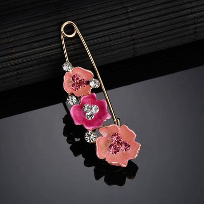 Floral brooch with pink flowers and clear gemstones on a dark background