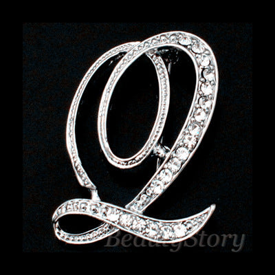 Silver brooch with a letter 'Q' design on a black background