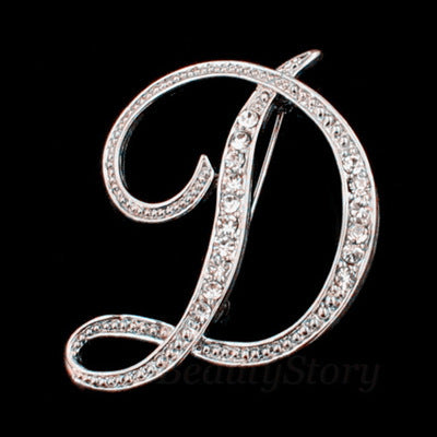 Silver brooch with letter 'D' design on a black background