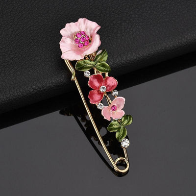 Floral brooch with pink flowers and green leaves on a black background