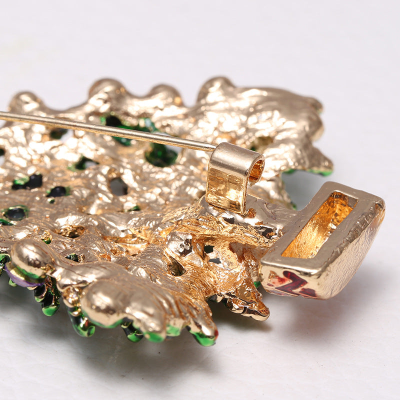 back side view of the brooch with green gemstones on a white background