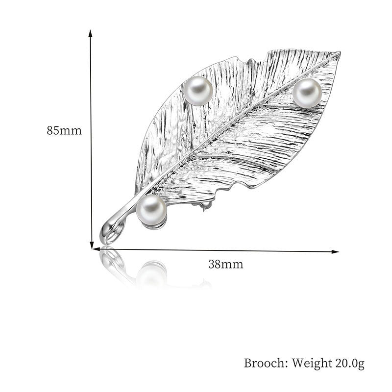 Leaf-shaped brooch with pearls and measurements on a white background