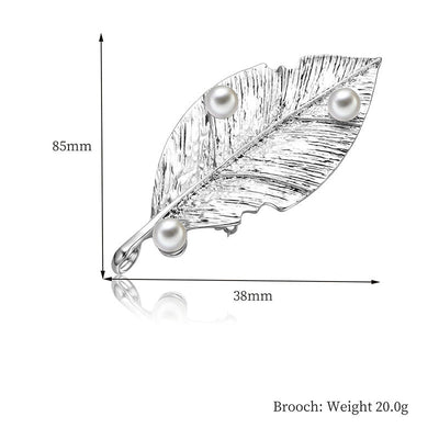 Leaf-shaped brooch with pearls and measurements on a white background
