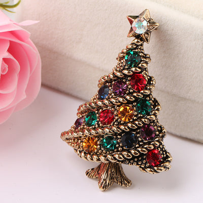 Christmas tree-shaped brooch with colorful gemstones on a light background