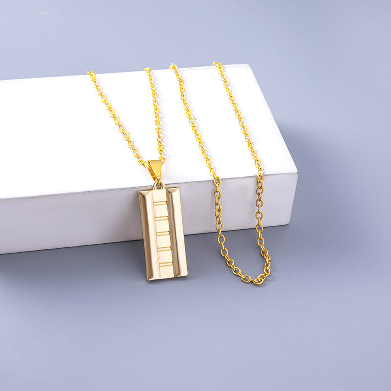 Gold necklace with a rectangular pendant on a light gray background