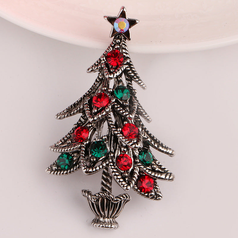Christmas tree brooch with red and green gemstones on a white background