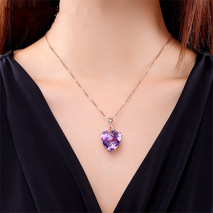 Necklace with a purple heart-shaped pendant worn by a person in a black top.