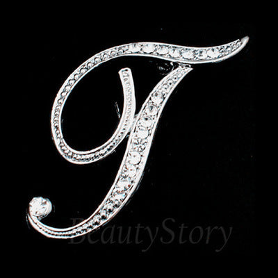 Silver letter 'T' brooch with crystals on a black background