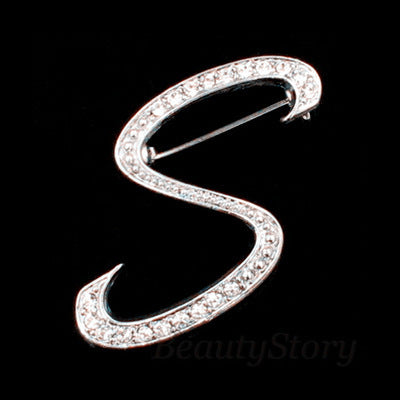 Silver brooch with rhinestones shaped like the letter 'S' on a black background.