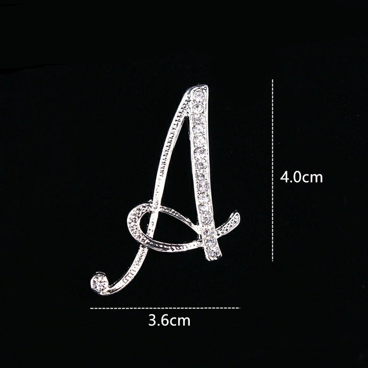 Silver brooch shaped like the letter 'A' with measurements on a black background
