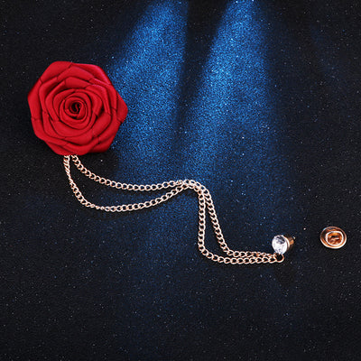 Red rose with a gold chain brooch on a dark blue fabric background