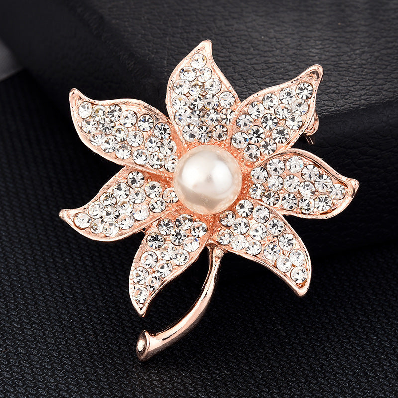 Decorative flower brooch with pearl center and rose gold accents on a black background
