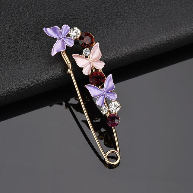 Decorative brooch with butterflies and gemstones on a dark surface