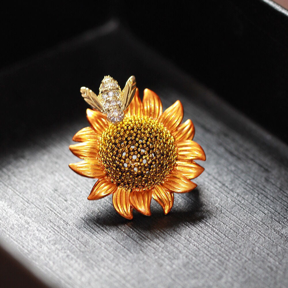 Sunflower-shaped brooch with a bee on a dark surface