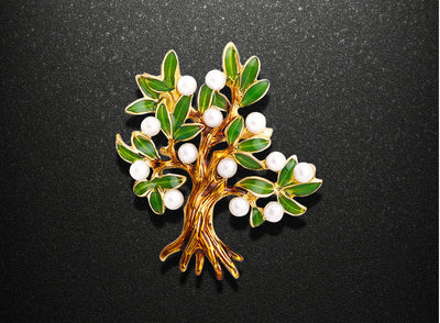 Tree-shaped brooch with green leaves and white berries on a black background