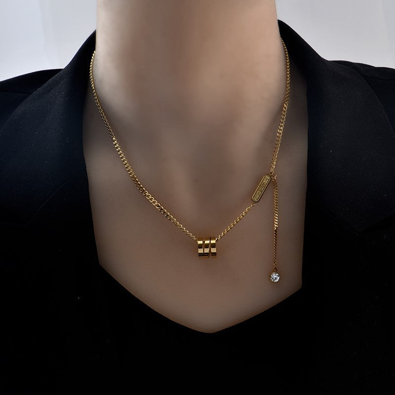 close up Gold tone necklace with a pendant on a mannequin against a black background