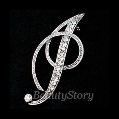 Silver brooch with intricate design letter I on a black background