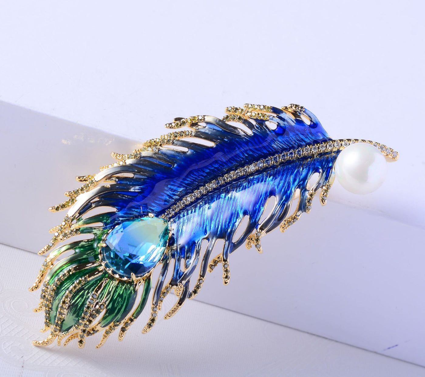 Decorative hair clip with blue and green feathers on a white background