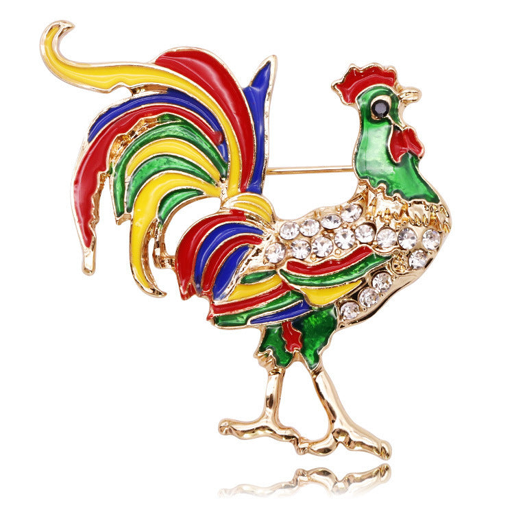 Colorful rooster-shaped brooch with gold accents on a white background