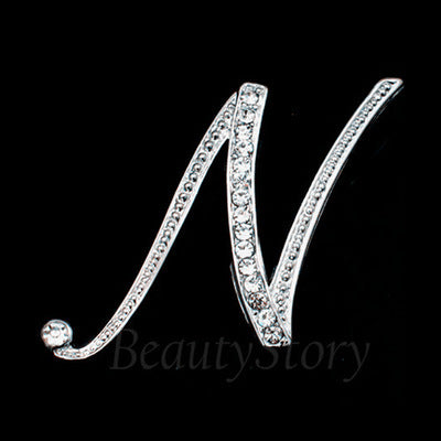 Silver brooch shaped like the letter 'N' with crystals on a black background