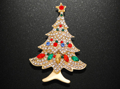 Christmas tree-shaped brooch with rhinestones on a black background