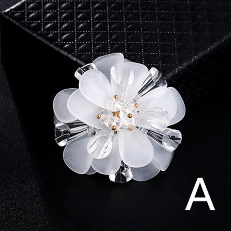 White floral brooch with clear crystals on a black background