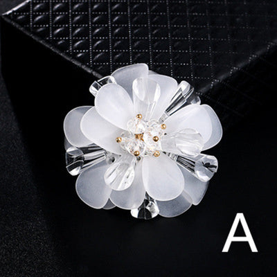 White floral brooch with clear crystals on a black background