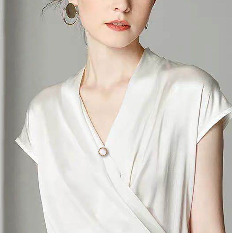 Woman wearing a white blouse and a magnetic brooch with a plain background