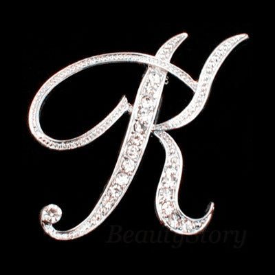 Silver brooch with the letter 'K' on a black background