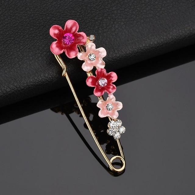 Floral brooch with pink flowers and gemstones on a black background