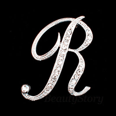 Silver brooch with letter 'R' design on a black background