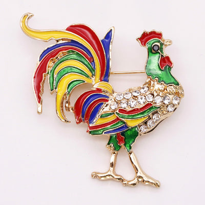 Colorful rooster-shaped brooch with rhinestones on a white background