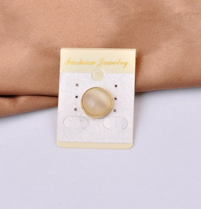 Gold and beige magnetic brooch  in Jewelry card on a beige fabric and white surface background