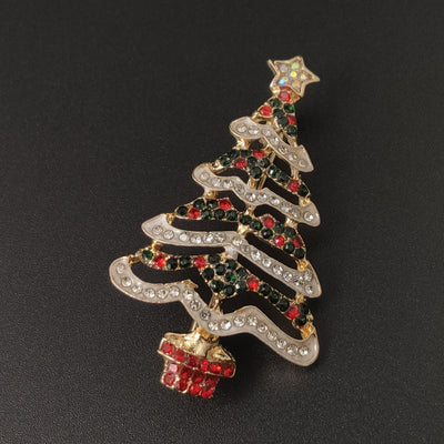 Christmas tree brooch with red and green accents on a black background