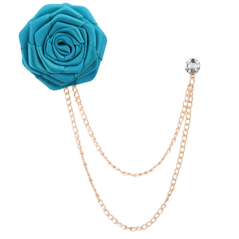 Blue rose-shaped brooch with gold chain on a white background