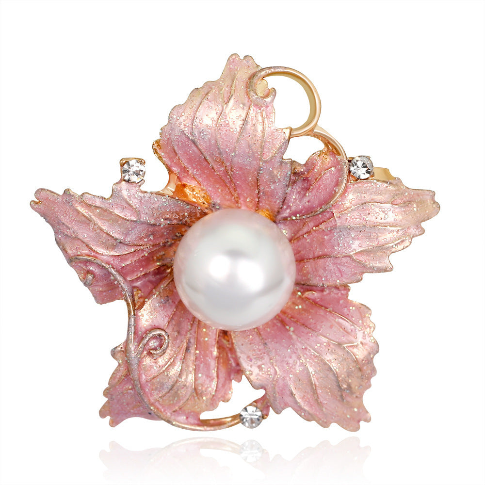 Pink leaf-shaped brooch with a pearl center on a white background
