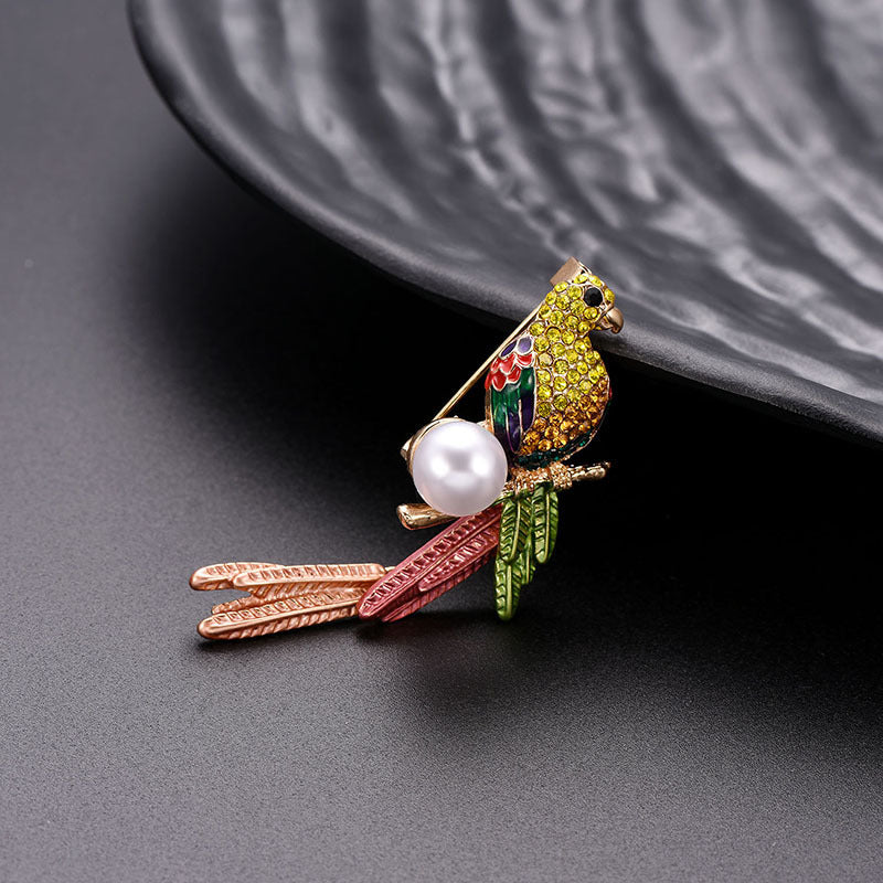 Colorful parrot brooch with pearl on a dark surface