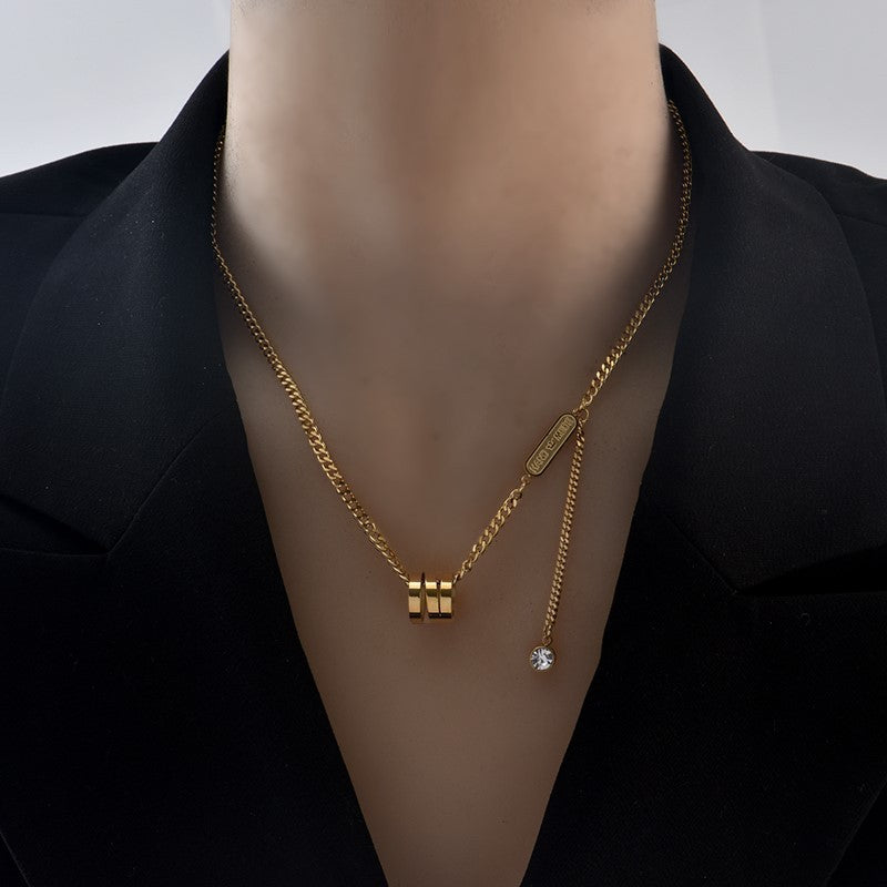 Golden color necklace with a pendant on a mannequin wearing a black outfit.