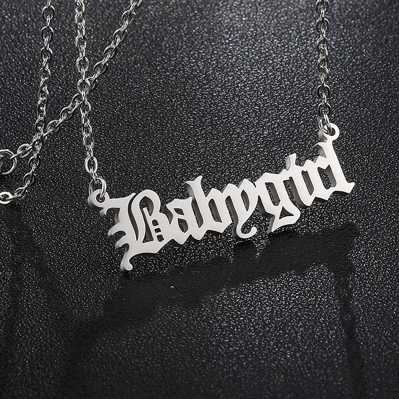 Silver 'Babygirl' necklace on a black textured background